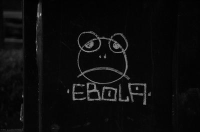 Graffiti on a newspaper dispenser; a frog-like circular face drawing with the word "EBOLA"