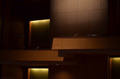 Photo of a split-level balcony in a darkened modern theater with yellow lighting.