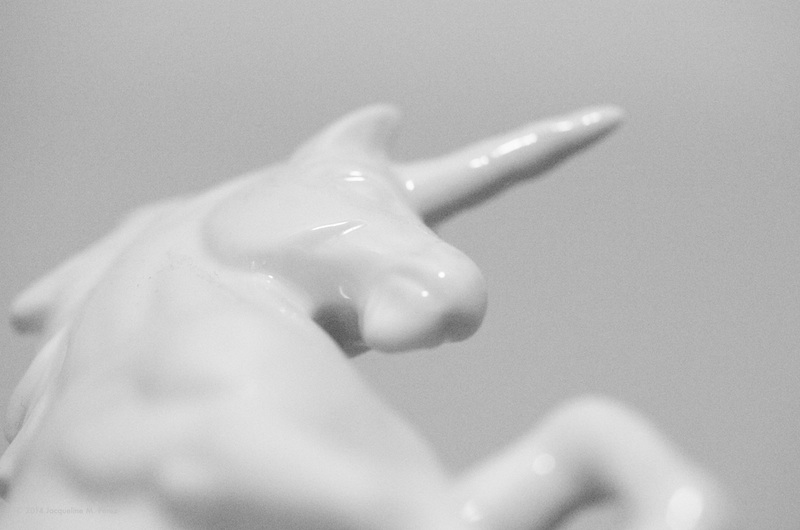The head and upper body of a white porcelain unicorn figurine photographed from a low angle.